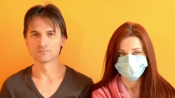 Muž a žena sedí na žlutém pozadí, dívka si sundá modrou masku, radují se — Stock video