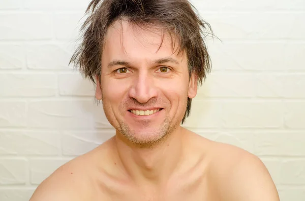 Emocional loco caucásico hombre con cerdas y pelo peludo, sin cierre, sonriendo felizmente sobre fondo de ladrillo blanco —  Fotos de Stock