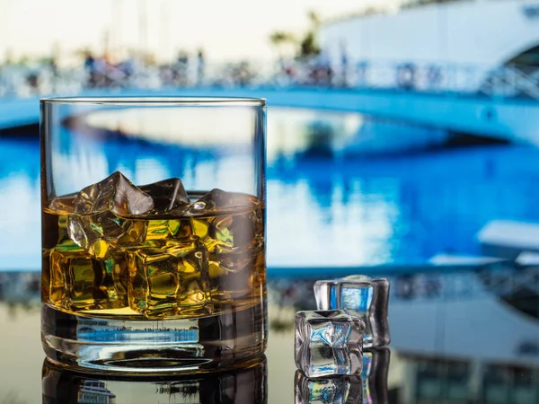 whiskey in a glass with ice on the background of the pool