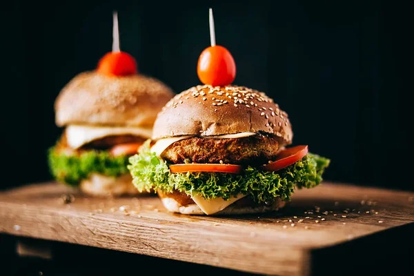 Sığır eti kesmek için kullanılan iki ağız sulandıran lezzetli ev yapımı hamburger. ahşap masanın üstünde. Eklenen bıçak hamburgerler.