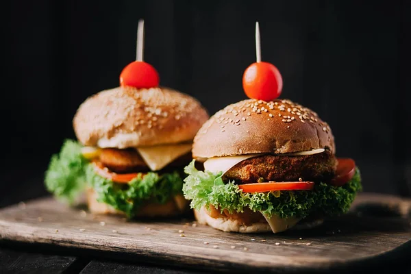 Sığır eti kesmek için kullanılan iki ağız sulandıran lezzetli ev yapımı hamburger. ahşap masanın üstünde. Eklenen bıçak hamburgerler.