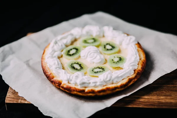 Kivi ve ahşap antika masa üzerinde krem şanti ile tart