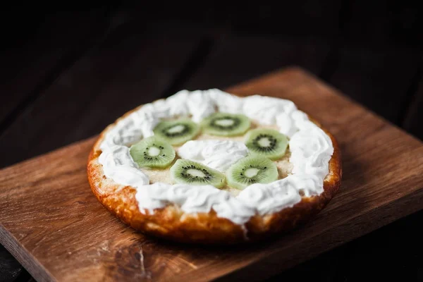 Kivi ve ahşap antika masa üzerinde krem şanti ile tart