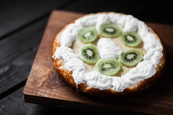 Kivi ve ahşap antika masa üzerinde krem şanti ile tart