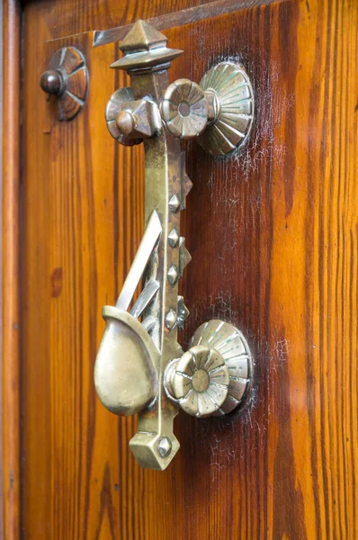 茶色の木製の都市のドアに古いブロンズのドア ハンドル — ストック写真