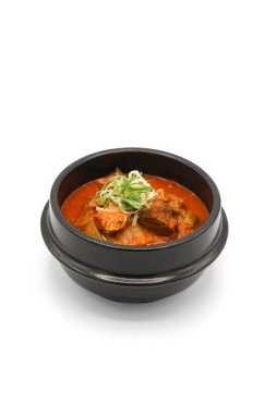 Stüdyo ışığı altında siyah taş kasede kimchi çorbası izole ettim. 