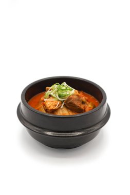 Stüdyo ışığı altında siyah taş kasede kimchi çorbası izole ettim. 