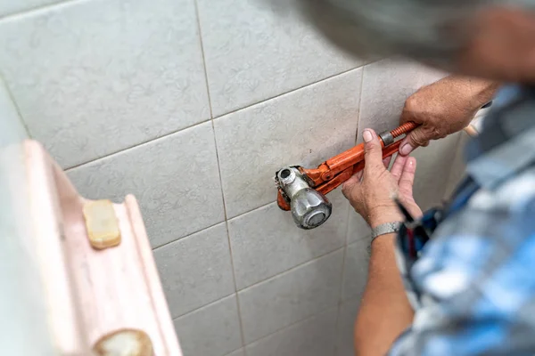 Asian man tries to fix and repair pipe / shower in the old restr — Stockfoto