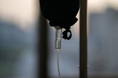 Tıbbi alete yaklaş, akşam penceresindeki karanlık siluet temasında salin damlası.