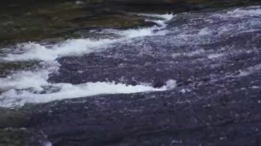 Kayanın zeminindeki şelaleden akan hızlı suya yaklaş..