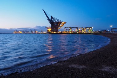 Felixstowe Limanı, Suffolk, İngiltere, 8 Mart 2020: Turnalar hava kararınca kargo gemilerine konteynır yüklüyorlar