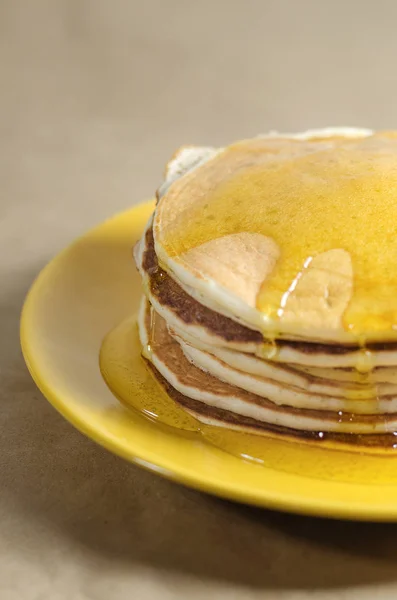 Stapel Pfannkuchen auf einem gelben Teller mit Honig — Stockfoto