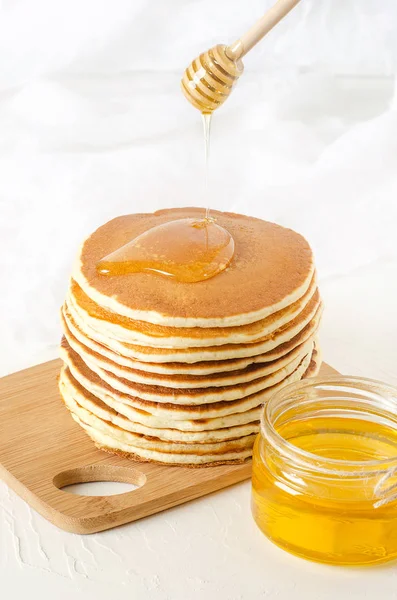 Стопка блинчиков на желтой тарелке с медом — стоковое фото