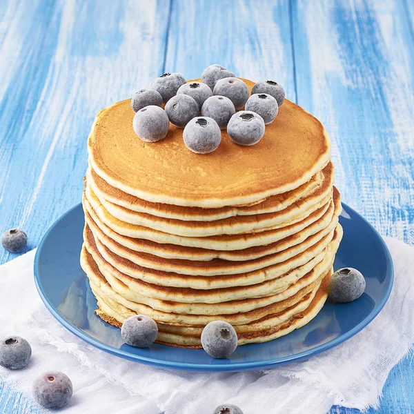 Stapel Pfannkuchen auf einem blauen Teller mit gefrorenen Blaubeeren — Stockfoto
