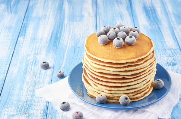 Pila de panqueques en un plato azul con arándanos congelados — Foto de Stock