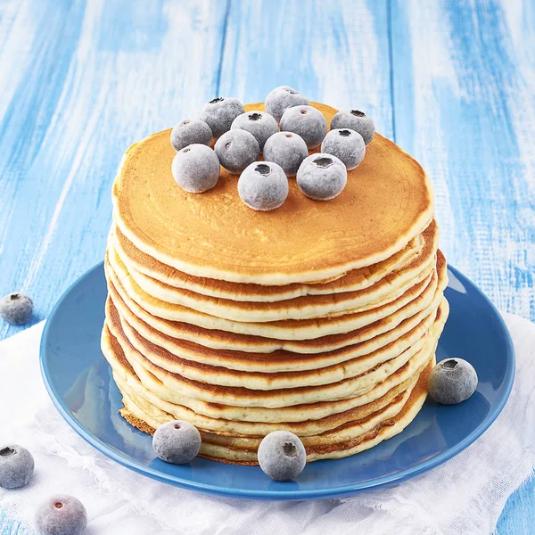 Stapel Pfannkuchen auf einem blauen Teller mit gefrorenen Blaubeeren — Stockfoto