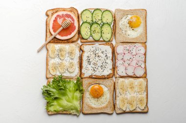 Beyaz bir arka plan üzerinde farklı tost. Yumurta, muz, salata, krem peynir, salatalık, turp, greyfurt ve bal tost.