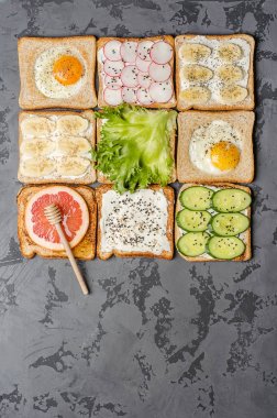 Gri bir arka plan üzerinde farklı tost. Yumurta, muz, salata, krem peynir, salatalık, turp, greyfurt ve bal tost.