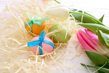 Paskalya Paskalya yumurtaları ile Lale Beyaz ahşap zemin üzerinde yuvadaki bileşimi