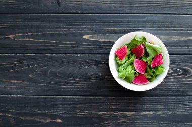 Karpuz turp (Çin daikon) ve metin için yer ahşap bir zemin üzerine beyaz bir tabak içinde marul salatası. Üstten Görünüm.