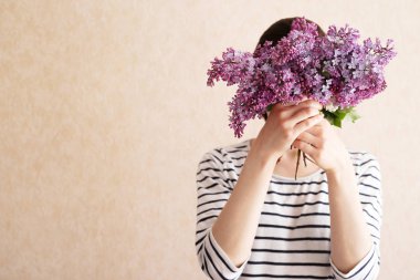 Metin için boş alan ile bej renkli arka plan üzerinde buket Lila çiçek kafasından gizleme kadın.