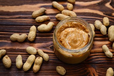 Kase fıstık ezmesi ve fıstık üst görünümden koyu ahşap arka plan üzerinde. Metin veya tasarım için alan.