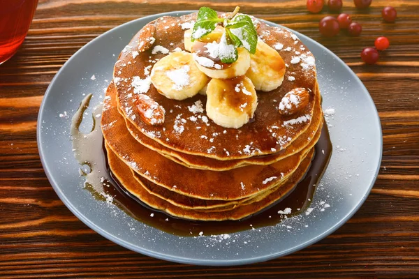 Pancakes with caramel, banana and nuts decorated with cranberries and mint with juice.