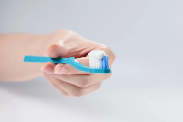 Woman holds toothbrush with toothpaste in her hand isolated on w — Stock Photo, Image