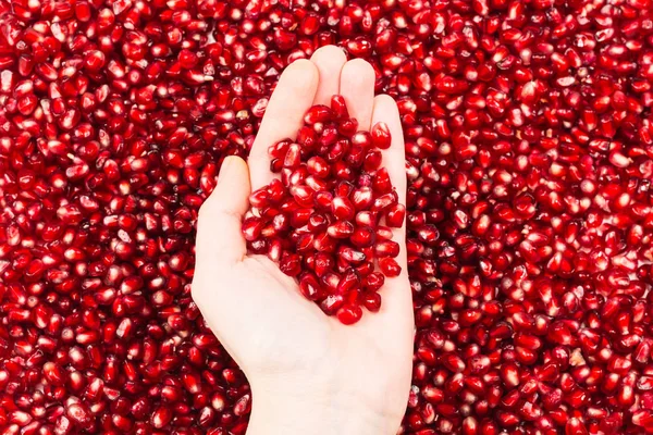 Rode sappige granaatappel zaden in de hand van de vrouw. — Stockfoto