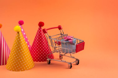 Alışveriş arabasında pembe fiyonklu mavi hediye kutusu ve doğum günü hediyesi.