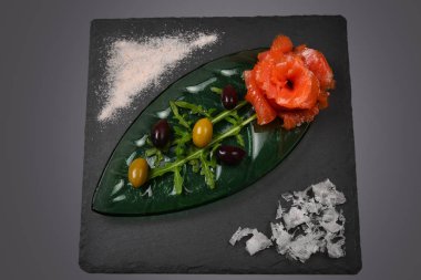 Beyaz üzerine tuz ve zeytinli bir tabakta somon dilimleri..