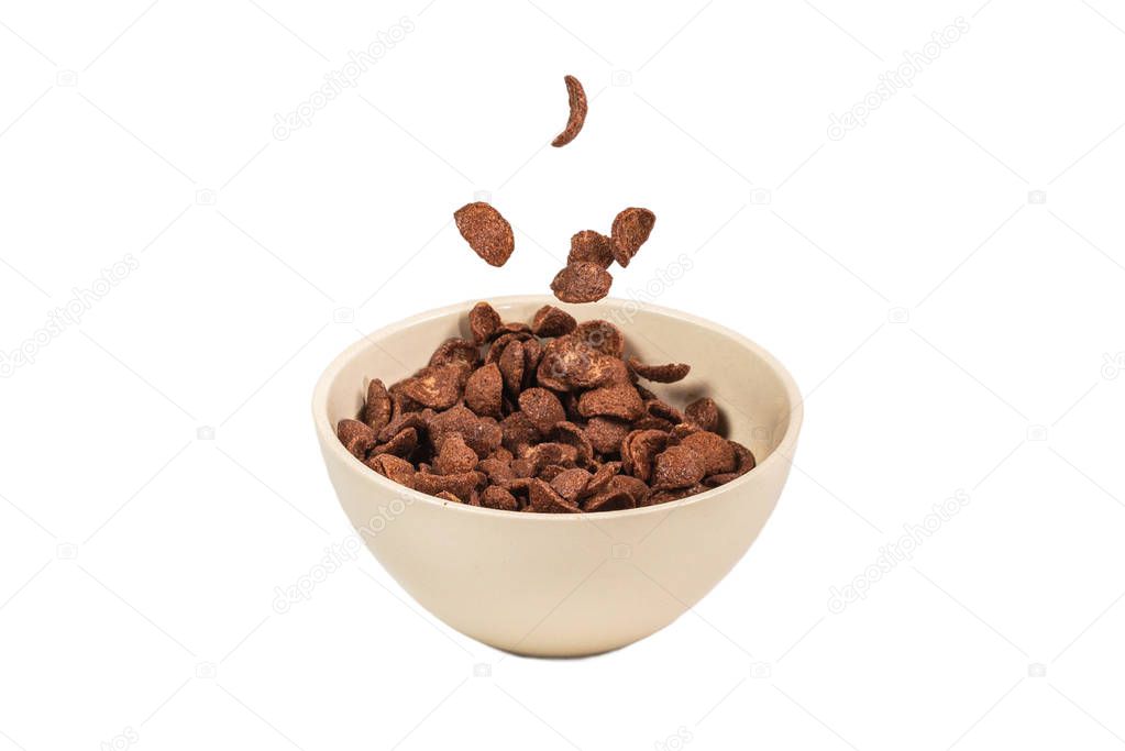 Chocolate corn flakes falling to the white bowl isolated on whit
