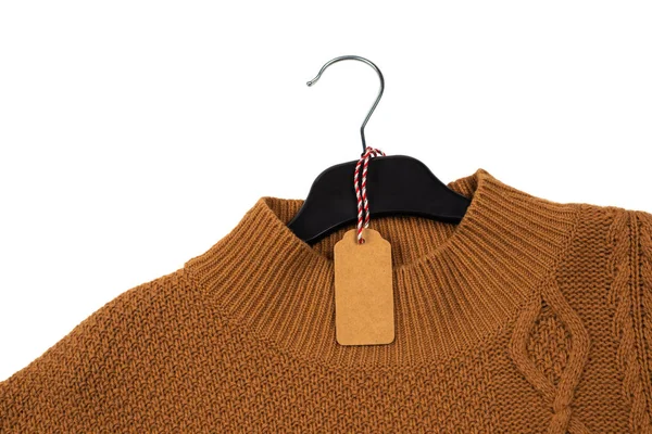 Kötött pulóver lóg egy fekete vállfán egy címkével. — Stock Fotó