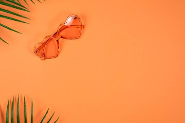 Pembe güneş gözlüğü ve turuncu arka planda bir şapka.. 