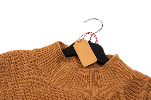 Knitted sweater hangs on a black hanger with a tag. — Stock Photo, Image