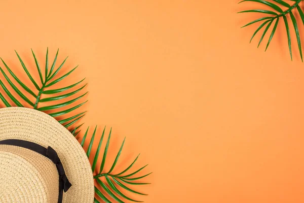 Yaz şapkası turuncu arka planda yeşil yaprağın üzerinde duruyordu.. 