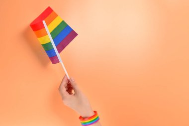 Turuncu arka planda kadın el LGBT bayrağı. Boşluk Kopyala. 