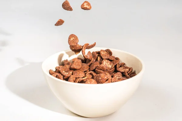Chocolate corn flakes falling to the white bowl isolated on whit — Stock Photo, Image