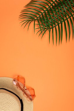 Pembe güneş gözlüğü ve turuncu arka planda bir şapka.. 