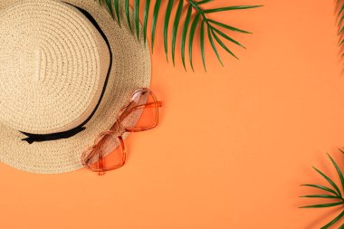 Pembe güneş gözlüğü ve turuncu arka planda bir şapka. Boşluğu kopyala. 