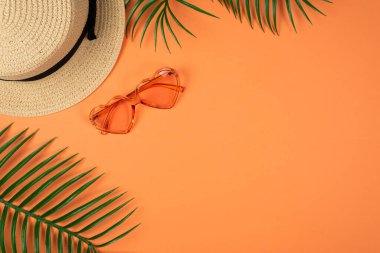 Pembe güneş gözlüğü ve turuncu arka planda bir şapka. Boşluğu kopyala. 