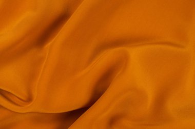 Altın ipek ya da saten lüks kumaş dokusu soyut bir arkaplan olarak kullanılabilir. Üst görünüm.