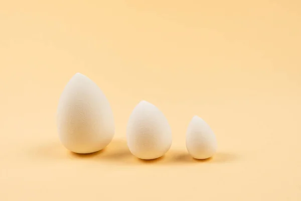 Small, medium and large white beauty blender on beige background. Copy space.