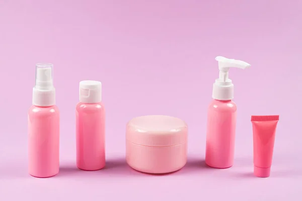 Pink plastic bottles for hygiene products, cosmetics, hygiene products on a pink background. Copy space.