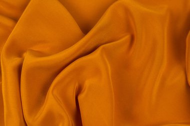 Altın ipek ya da saten lüks kumaş dokusu soyut bir arkaplan olarak kullanılabilir. Üst görünüm.