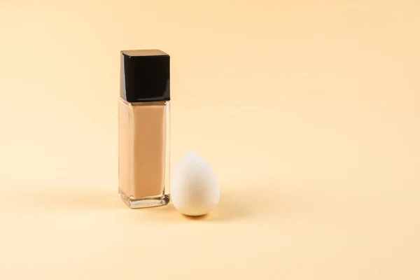 Small, medium and large  white beauty blender and makeup foundation on beige background. Top view.