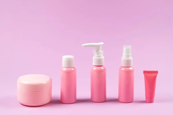 Pink plastic bottles for hygiene products, cosmetics, hygiene products on a pink background. Copy space.