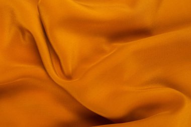 Altın ipek ya da saten lüks kumaş dokusu soyut bir arkaplan olarak kullanılabilir. Üst görünüm.