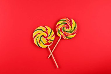 Kırmızı arka planda renkli şekerler. Lolipop. Üst te. Kopyalama alanı.