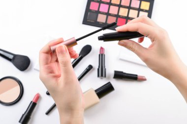 Mascara kadınların elinde. Profesyonel makyaj ürünleri kozmetik güzellik ürünleri, temel, ruj, göz farı, göz kirpikleri, fırçalar ve aletler.